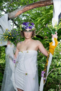 Ormanda poz veren bir çiçek çelengi içinde güzel bir gelin.