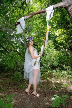 Ormanda poz veren bir çiçek çelengi içinde güzel bir gelin.