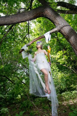 Ormanda poz veren bir çiçek çelengi içinde güzel bir gelin.