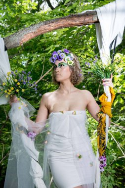 Ormanda poz veren bir çiçek çelengi içinde güzel bir gelin.