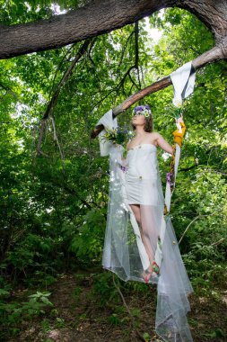 Ormanda poz veren bir çiçek çelengi içinde güzel bir gelin.