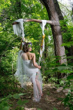 Ormanda poz veren bir çiçek çelengi içinde güzel bir gelin.