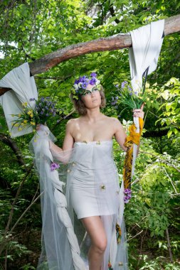 Ormanda poz veren bir çiçek çelengi içinde güzel bir gelin.