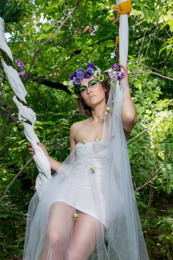 Ormanda poz veren bir çiçek çelengi içinde güzel bir gelin.