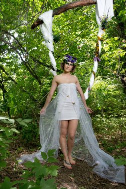 Ormanda poz veren bir çiçek çelengi içinde güzel bir gelin.