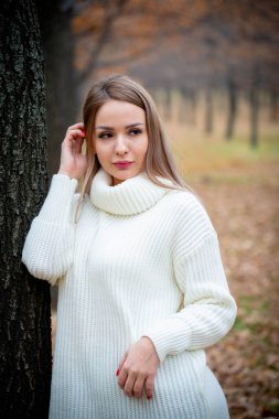 Güz parkında poz veren güzel bir kadın. 