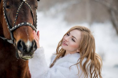 Güzel kız, kışın atıyla dışarıda poz veriyor. 