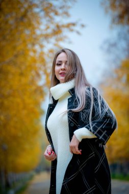 Güz parkında poz veren güzel bir kadın. 