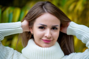 Açık havada beyaz kazak giyen güzel bir kadının portresi. 