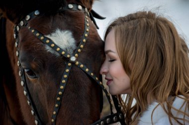 Güzel kız, kışın atıyla dışarıda poz veriyor. 