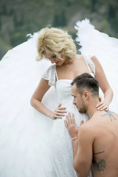 pregnant woman with angel wings posing with husband