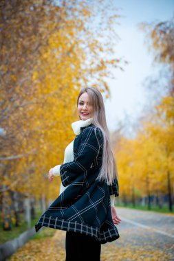 Güz parkında poz veren güzel bir kadın. 