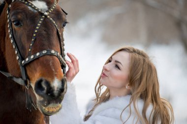 Güzel kız, kışın atıyla dışarıda poz veriyor. 