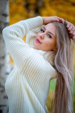 Güz parkında poz veren güzel sarışın bir kadının portresi.