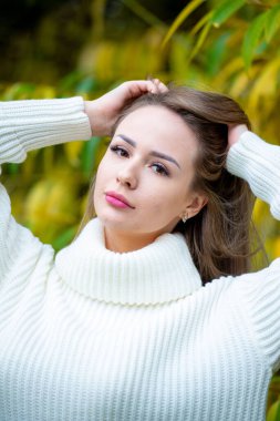 Açık havada beyaz kazak giyen güzel bir kadının portresi. 