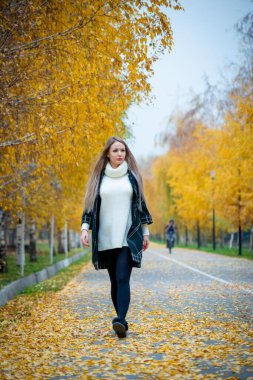 Güz parkında poz veren güzel bir kadın. 