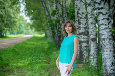 Güzel kız huş ağaçlarına karşı poz veriyor