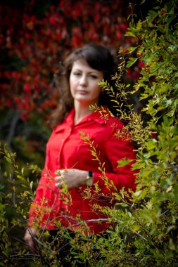 Güzel bir kadın dışarıda poz veriyor, kırmızı gömlek giyiyor.