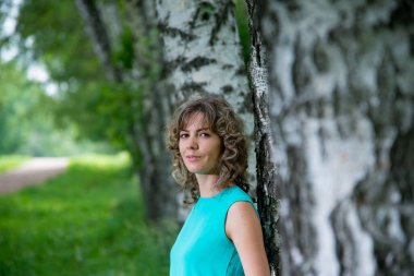 Güzel bir kadın huş ağaçlarının yanında poz veriyor.