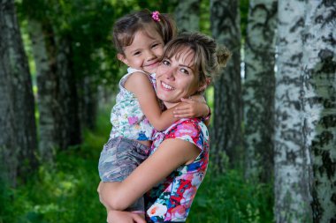 Anne ve kızı yaz parkında poz veriyorlar.