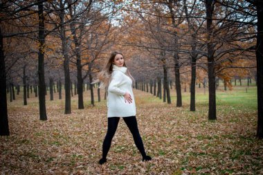 Güz parkında poz veren güzel bir kadın. 