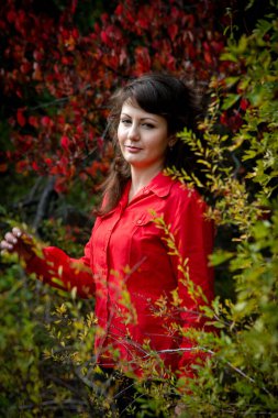 Güzel bir kadın dışarıda poz veriyor, kırmızı gömlek giyiyor.