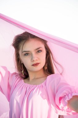 Terasta poz veren pembe elbiseli güzel bir kadın. 