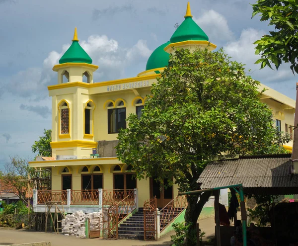 Sebuah masjid kuning besar dengan kubah hijau di dekat foto pohon besar yang diambil di Indonesia. — Stok Foto