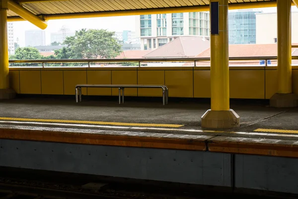 Banco vacío en la estación de tren con vista a la ciudad y arbustos foto tomada en Yakarta Indonesia — Foto de Stock