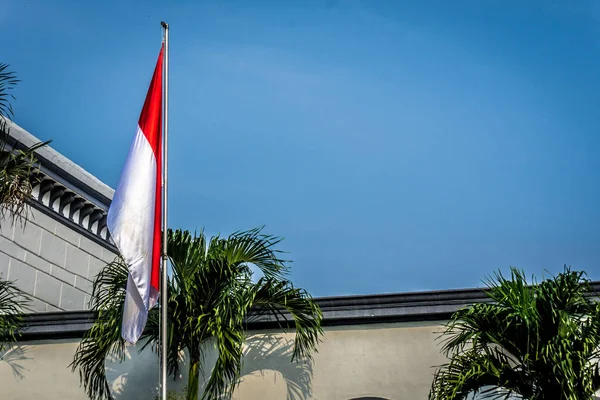 Indonesia flag on the mast with building as background