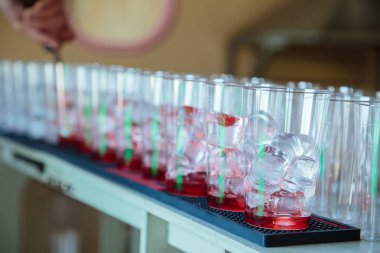 Sayaç Bar. Barda barmen yaz serinletici meyve alkolsüz kokteyller hazırlamaktadır. Barmen meyve şurubu bardak buz parçaları ile içine dökülen 