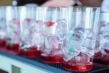 Sayaç Bar. Barda barmen yaz serinletici meyve alkolsüz kokteyller hazırlamaktadır. Barmen meyve şurubu bardak buz parçaları ile içine dökülen 