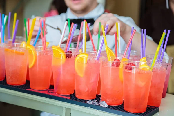 Non-alcoholic cocktails. Fruit and berry cocktails with colored tubules. Fitness Bar. The barman prepares fruit cocktails.