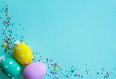 Paskalya arka plan. Çeşitli renklerde dekore edilmiş Paskalya yumurtaları, turkuaz bir arka plan üzerinde çok renkli toz. Boş alan