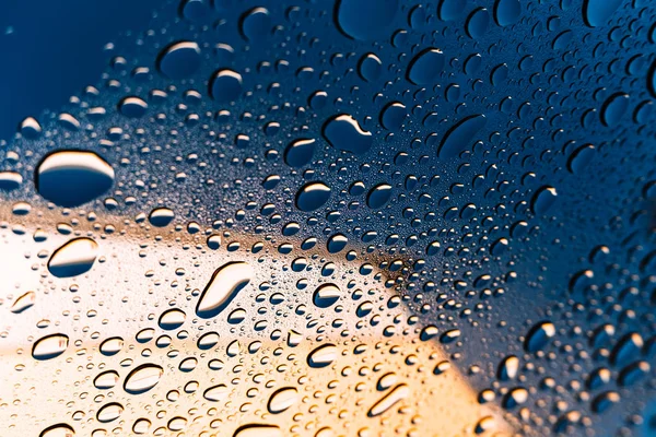The texture of water droplets on the glass, textured natural gradient of reflections of the blue sky and yellow wall.