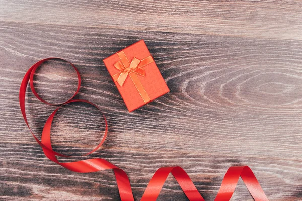 Red box and ribbon on a wooden background