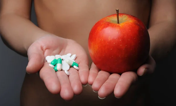 Girl holds pills in one hand.Pills versus fruits.