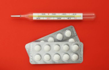 Kırmızı arka planda termometre hapları. Grip salgını, koronavirüs. Sıcaklık 37.2 C.