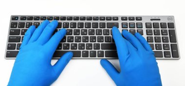 Varşova, Polonya - 21 Mart 2020: Dell Premier KM717 Black / Gray BTA üyesi parlak sarı lastik eldivenli adam klavyede yazı yazıyor. Halka açık yerlerde dezenfeksiyon, virüse karşı mücadele.