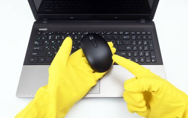 Halka açık yerlerde dezenfeksiyon, virüse karşı mücadele, koronavirüs. Kauçuk eldivenli çalışan bir el, bir bilgisayar faresini işaret ediyor. Bahar genel veya düzenli temizlik.