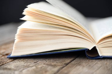 Siyah arka planı olan eski ahşap bir masada açık bir kitap..