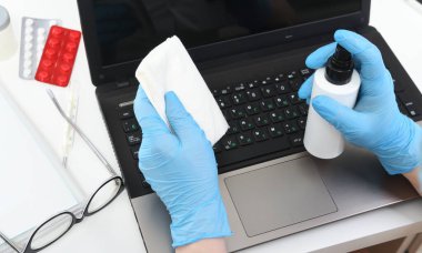 Halka açık yerlerde dezenfeksiyon, virüse karşı mücadele, koronavirüs. Çalışan bir el dizüstü bilgisayarın klavyesini siler. Hizmetçi ya da ev hanımı evle ilgilenir. Genel ya da düzenli temizlik.