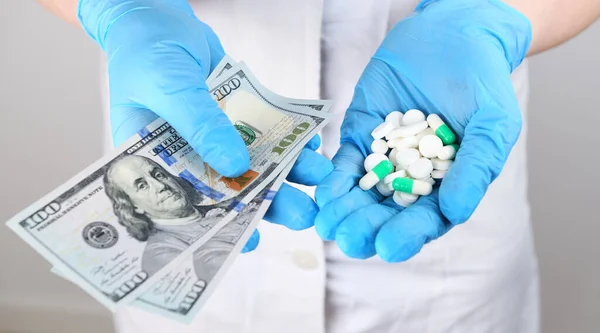 Medicine. A woman doctor in rubber gloves holds in one tablet and in another 200 two hundred dollars. Life saving service, legal pharmacy, prescribes medicines. Sale of drugs in the hospital.