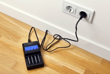 Warszawa, Polonya 4 Mart 2020: Panasonic Eneloop Pro şarj edilebilir nikel metal hidrit (Ni-MH) bataryaları. Parke katta şarj edici PANASONIC ENELOOP BQ CC65 LCD.