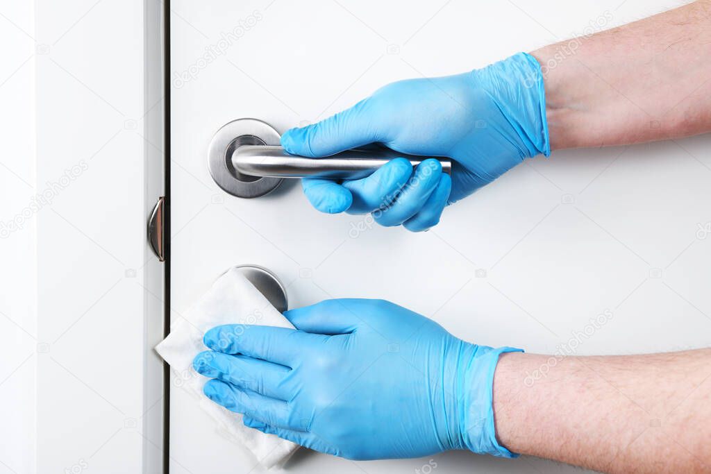Disinfection in public places, the fight against the virus, coronavirus.Worker's hand wipes the door handles. A maid or housewife takes care of the house. Spring general or regular cleaning.