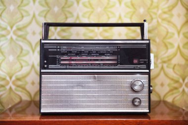 Odadaki komodinin üzerindeki antika radyo eski duvar kağıdının arka planına karşı..