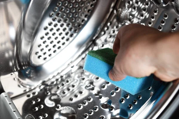 A man 's hand using a sponge cleans the drum of the washing machine.Drum of washing machine dry and clean close-up.Washing Dryer Machine inside view of a drum.