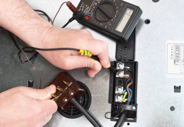 Profesyonel bir elektrikçi, yemek pişirme indüksiyon yüzeyindeki bağlantı kalitesini, bağlantıyı ve voltajı bir testçinin yardımıyla kontrol eder. Elektrikli ocakta sorun var..