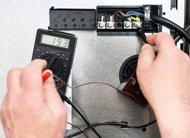 Profesyonel bir elektrikçi, yemek pişirme indüksiyon yüzeyindeki bağlantı kalitesini, bağlantıyı ve voltajı bir testçinin yardımıyla kontrol eder. Elektrikli ocakta sorun var..
