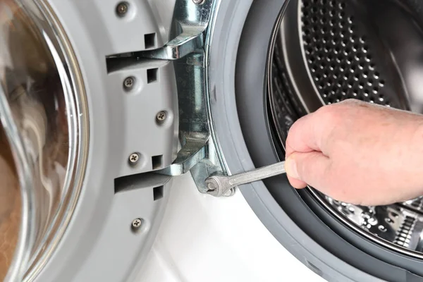 Repair and maintenance of the washing machine. The worker unscrews the door of the washing machine using a key.